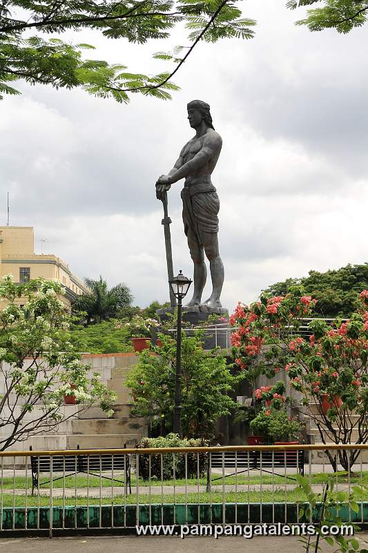 Lapu-lapu monument side view with clouds and flowers deside the Department of Tourism